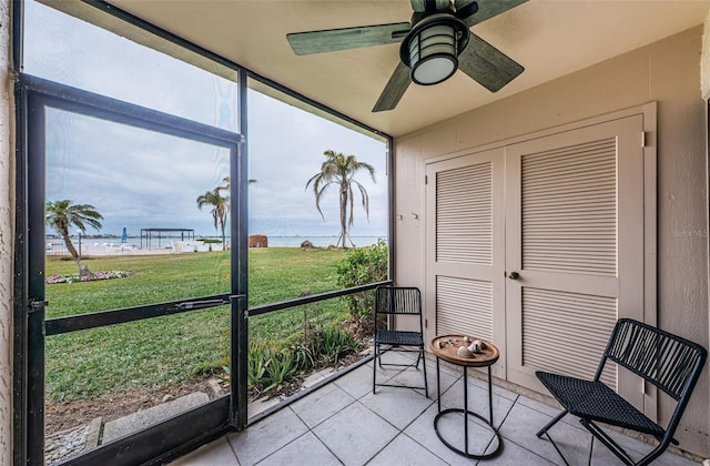 sunroom / solarium with plenty of natural light, ceiling fan, and a water view