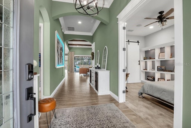 entrance foyer featuring crown molding, a barn door, ceiling fan, and light hardwood / wood-style floors