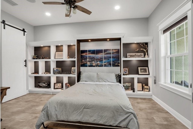 bedroom with multiple windows, a barn door, and ceiling fan