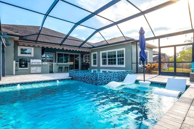 view of swimming pool featuring an outdoor bar, a patio, glass enclosure, area for grilling, and pool water feature