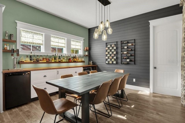 dining area featuring light wood-type flooring, wood walls, and bar
