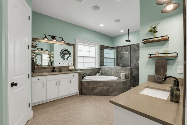 full bath with a bath, two vanities, a sink, and walk in shower