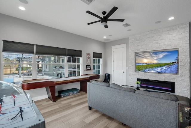 living room featuring ceiling fan, a fireplace, visible vents, recessed lighting, and wood finished floors