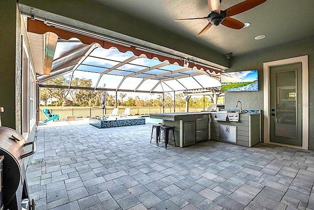 view of patio / terrace with a fenced backyard, glass enclosure, exterior kitchen, and outdoor dry bar