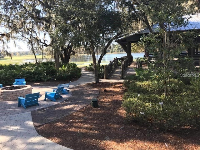 view of community with a water view, a patio, and an outdoor fire pit