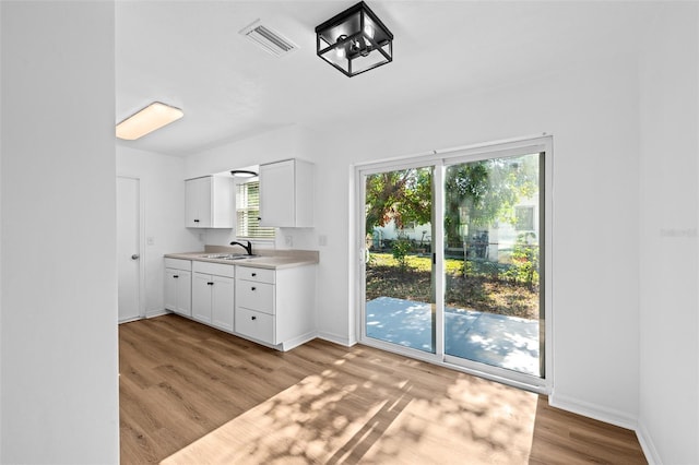 interior space featuring sink, white cabinets, and light wood-type flooring