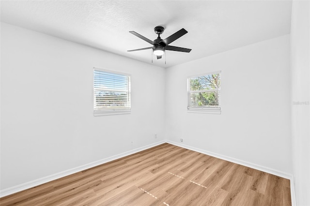 empty room with ceiling fan, plenty of natural light, and light wood-type flooring