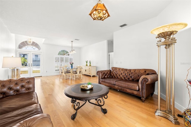 living room with a notable chandelier, wood-type flooring, and french doors