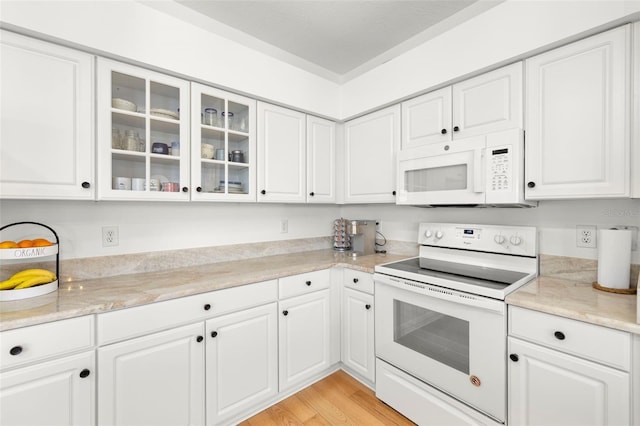 kitchen featuring light stone counters, white cabinets, white appliances, and light hardwood / wood-style flooring