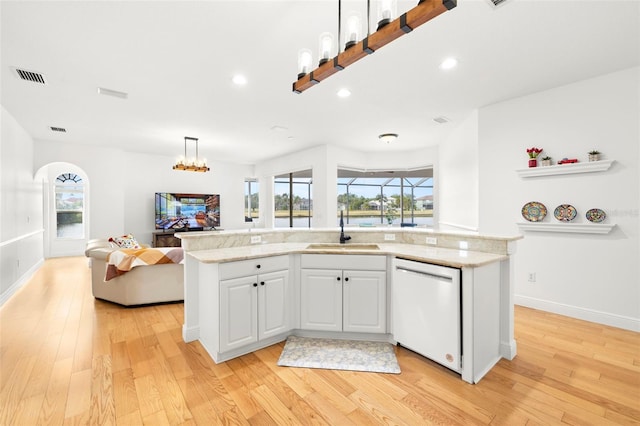 kitchen with decorative light fixtures, white cabinetry, dishwasher, sink, and a kitchen island with sink