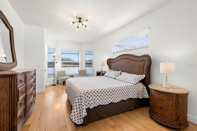 bedroom featuring an inviting chandelier and light hardwood / wood-style floors