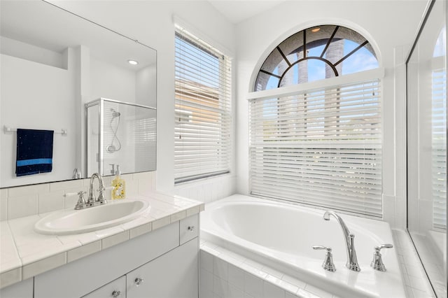 bathroom with shower with separate bathtub, a healthy amount of sunlight, and vanity