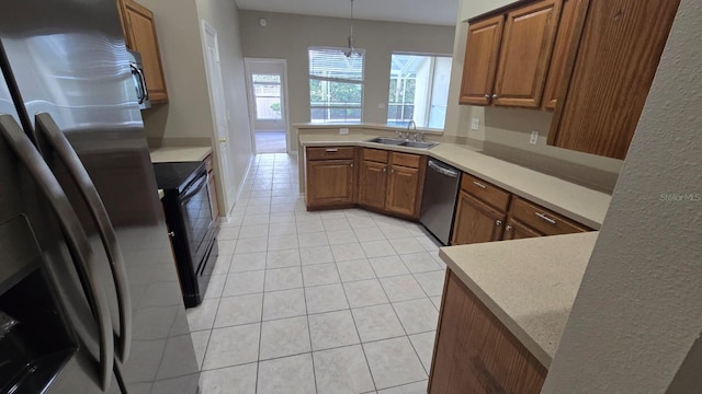 kitchen featuring sink, decorative light fixtures, light tile patterned floors, appliances with stainless steel finishes, and kitchen peninsula