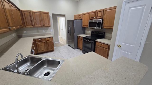 kitchen featuring stainless steel appliances, kitchen peninsula, sink, and light tile patterned floors