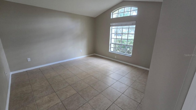 tiled spare room featuring vaulted ceiling and a wealth of natural light