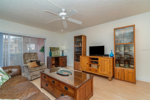 living room with ceiling fan, light hardwood / wood-style floors, and a textured ceiling