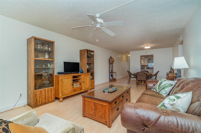 living room featuring ceiling fan, a textured ceiling, and light hardwood / wood-style flooring