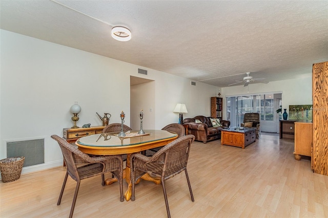 dining space with ceiling fan, light hardwood / wood-style floors, and a textured ceiling