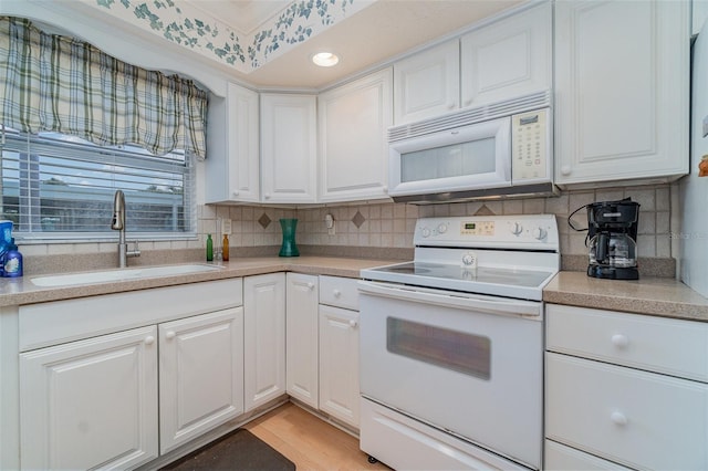 kitchen featuring sink, white appliances, white cabinetry, light hardwood / wood-style floors, and decorative backsplash