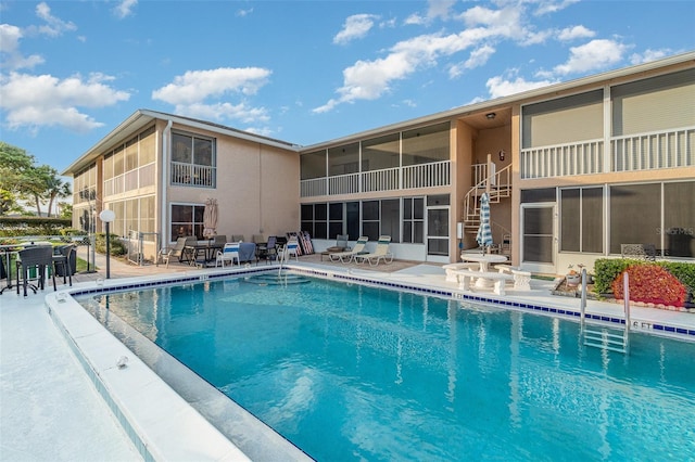 view of swimming pool with a patio area and a sunroom