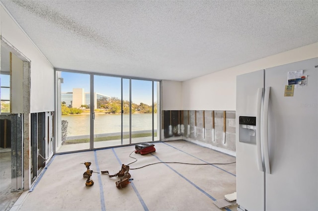 unfurnished room with a water view, expansive windows, and a textured ceiling