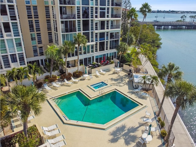 view of pool featuring a community hot tub, a patio, and a water view