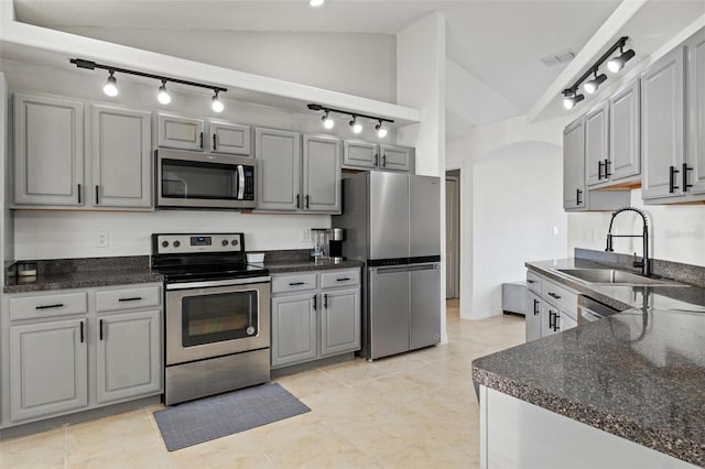 kitchen with lofted ceiling, stainless steel appliances, sink, and gray cabinetry