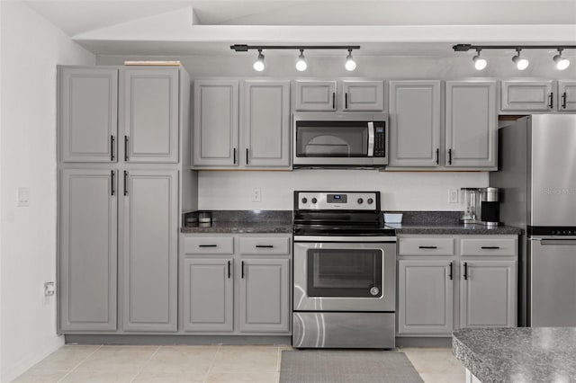 kitchen featuring light tile patterned flooring, lofted ceiling, appliances with stainless steel finishes, and gray cabinetry