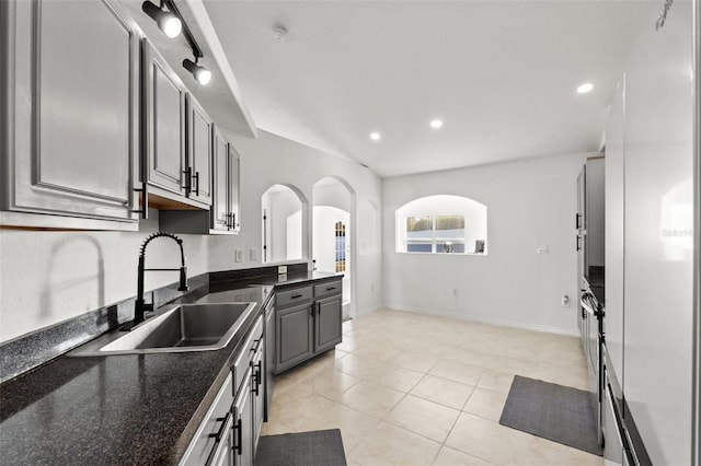 kitchen featuring light tile patterned floors, dark stone countertops, sink, and gray cabinetry