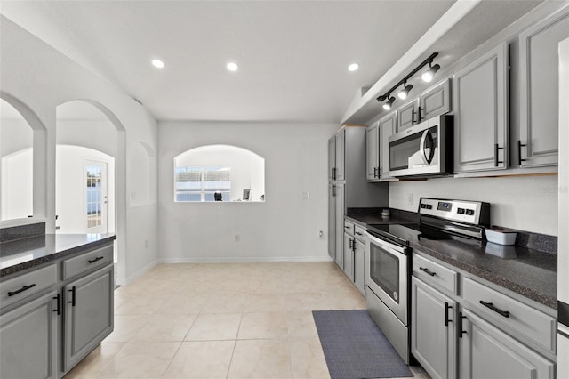 kitchen featuring dark stone countertops, stainless steel appliances, light tile patterned floors, and gray cabinetry