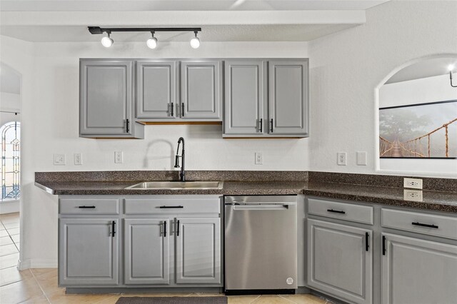 kitchen featuring sink, stainless steel dishwasher, light tile patterned floors, and gray cabinetry