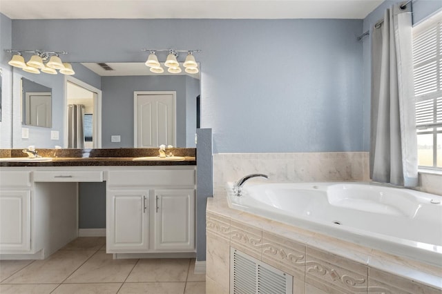 bathroom with tile patterned flooring, vanity, and tiled bath