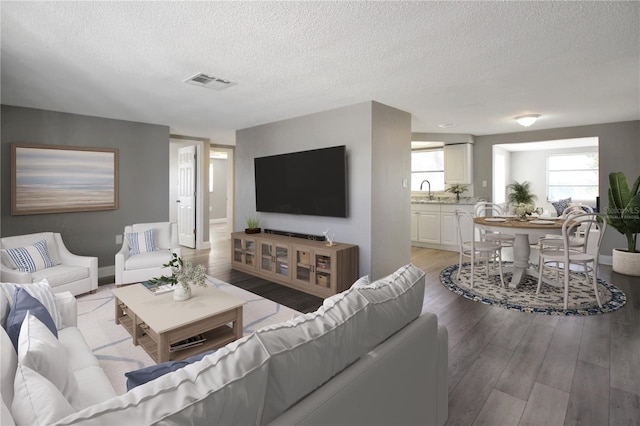 living room featuring sink, a textured ceiling, and light wood-type flooring