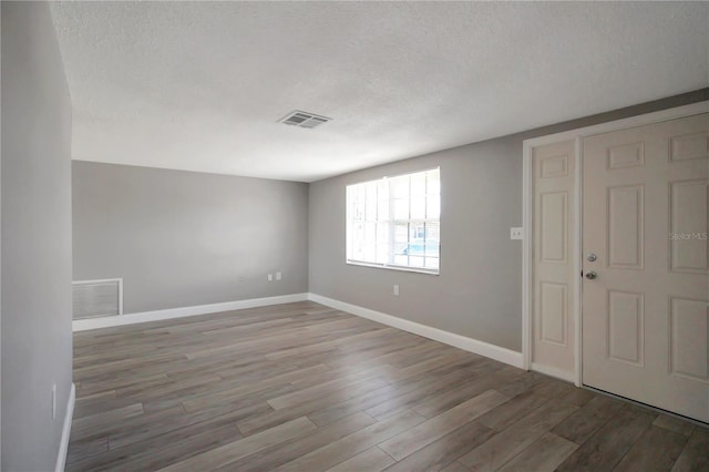 unfurnished room with hardwood / wood-style floors and a textured ceiling