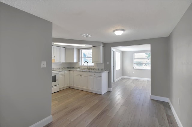 kitchen with white cabinetry, white electric range oven, light stone counters, and light wood-type flooring