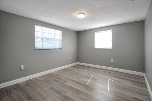 unfurnished room with a textured ceiling and light wood-type flooring