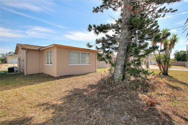 view of side of property featuring central AC and a lawn