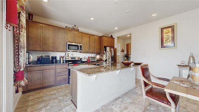 kitchen with a breakfast bar, sink, dark stone countertops, a kitchen island with sink, and stainless steel appliances