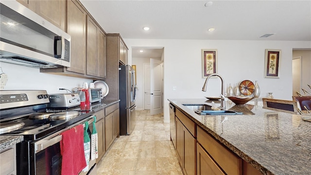 kitchen with stainless steel appliances, sink, and dark stone counters