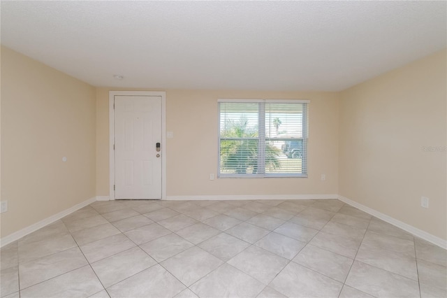 unfurnished room with light tile patterned floors, baseboards, and a textured ceiling