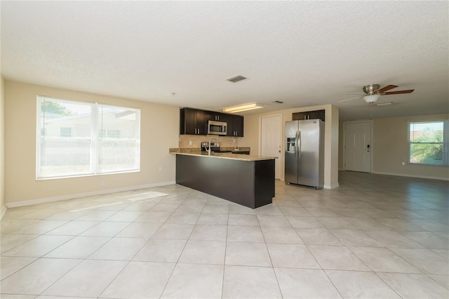 kitchen with open floor plan, a peninsula, stainless steel appliances, a ceiling fan, and a sink