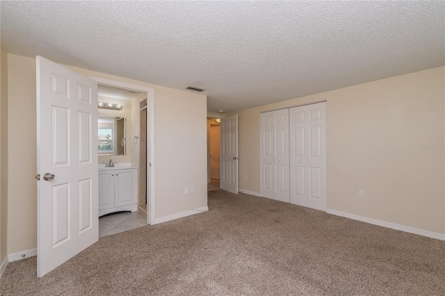 unfurnished bedroom featuring visible vents, light carpet, a textured ceiling, and a closet