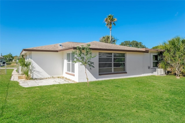 back of house with a lawn and stucco siding