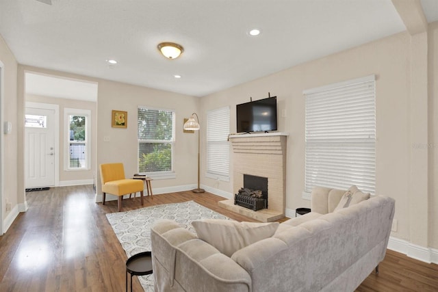 living room featuring wood-type flooring and a brick fireplace