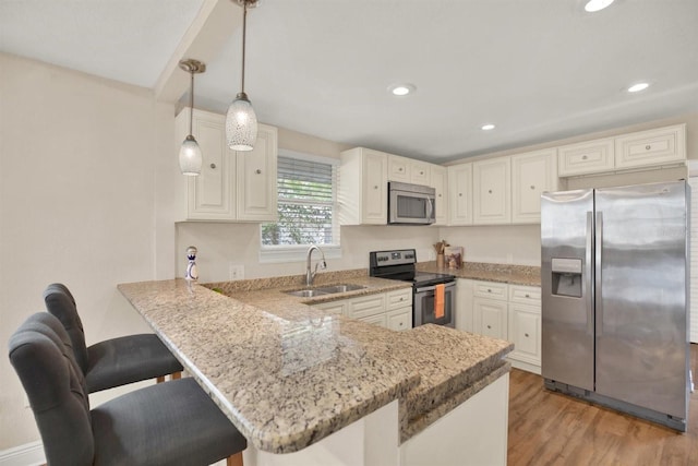 kitchen featuring stainless steel appliances, sink, a breakfast bar, and kitchen peninsula