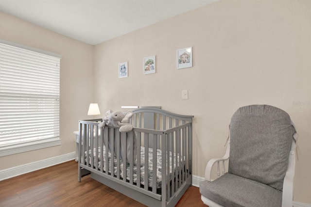 bedroom featuring a nursery area and dark hardwood / wood-style floors