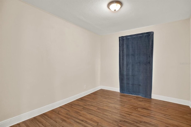 empty room featuring wood-type flooring and a textured ceiling