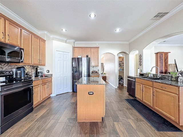 kitchen with stainless steel appliances, a center island, dark stone countertops, and dark hardwood / wood-style floors