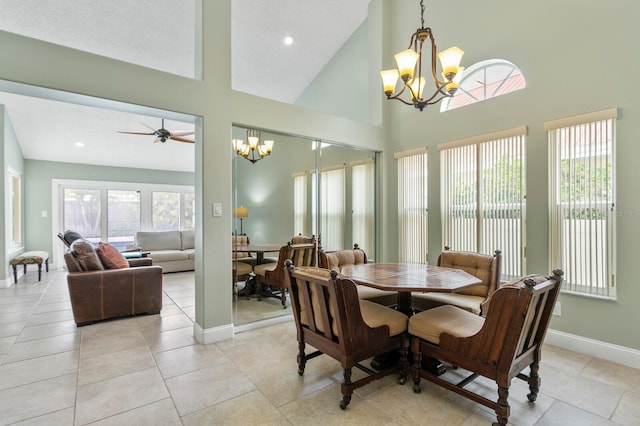 dining space featuring ceiling fan with notable chandelier, a wealth of natural light, high vaulted ceiling, and light tile patterned floors