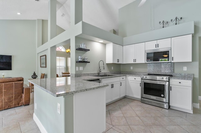 kitchen with sink, white cabinetry, appliances with stainless steel finishes, kitchen peninsula, and light stone countertops